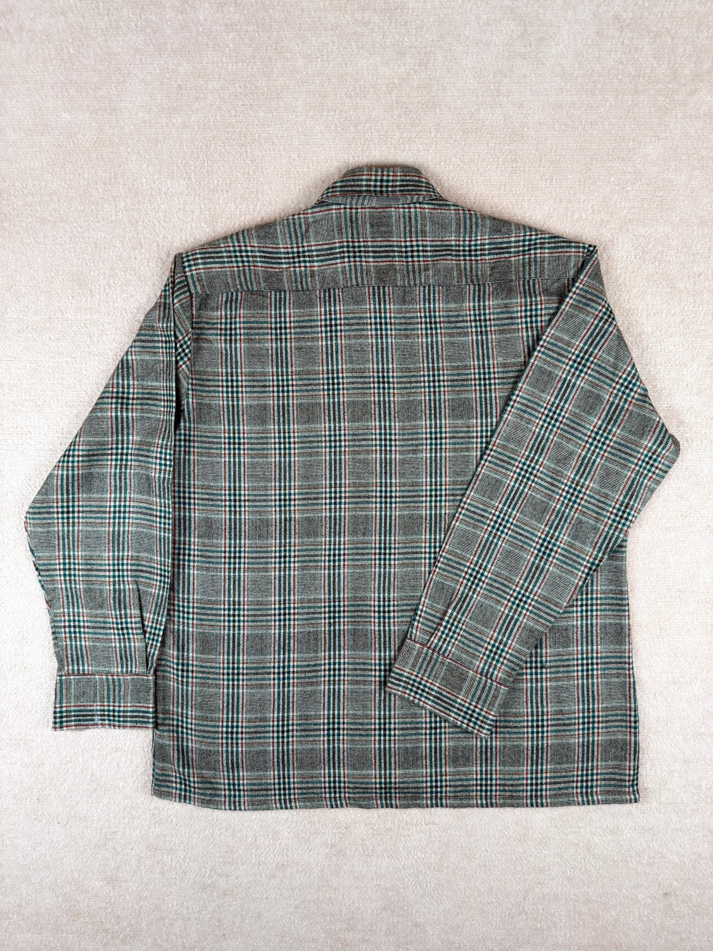 Green and gray plaid shirt on a light gray background