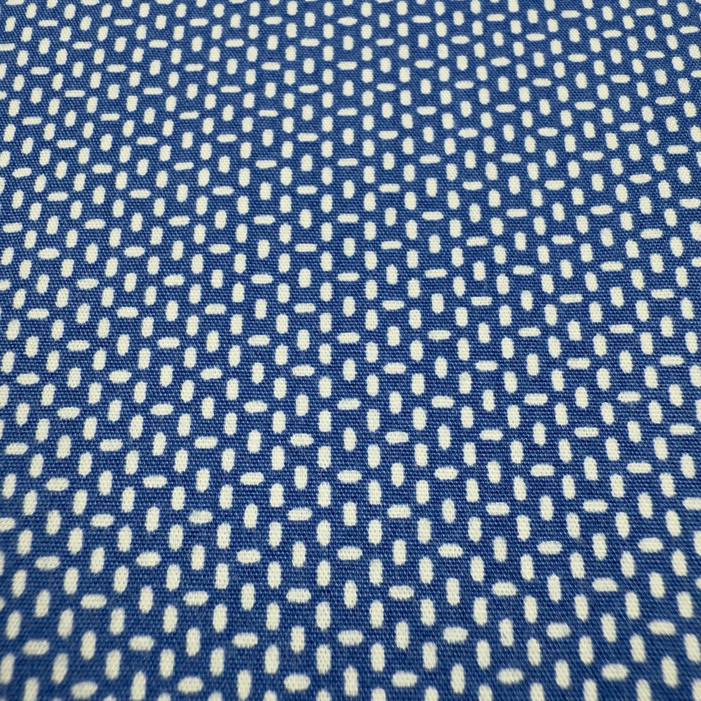 Close-up of white micro dot pattern on navy cotton shirt fabric