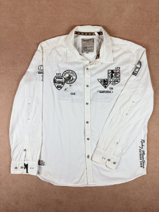 White denim shirt with embroidered patches on a brown background
